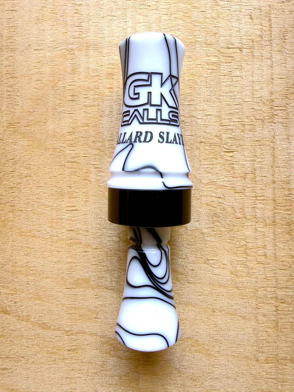 GK Calls Mallard Slayer duck call in Stormtrooper, white with black swirl, lying on a wood board