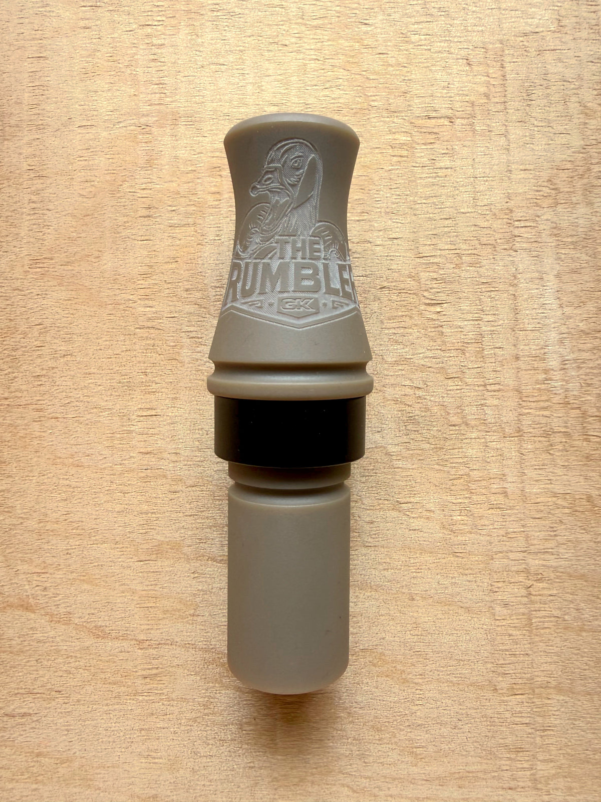 GK Calls The Rumbler goose call in Desert Tan, lying on a wood board