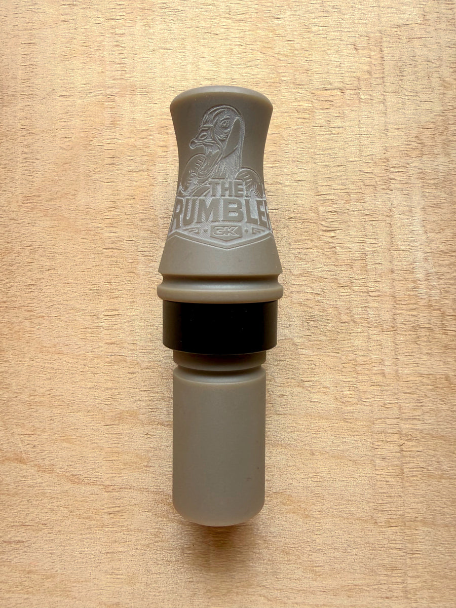 GK Calls The Rumbler goose call in Desert Tan, lying on a wood board