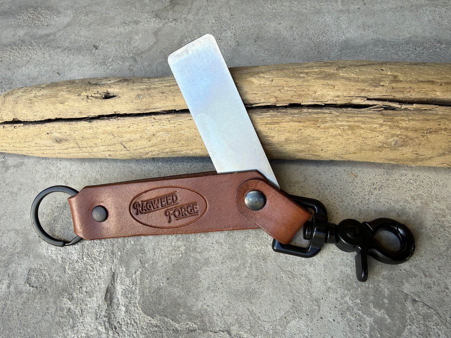 Diamond sharpening plate swung out of a brown leather holder with a clip and key ring, on driftwood