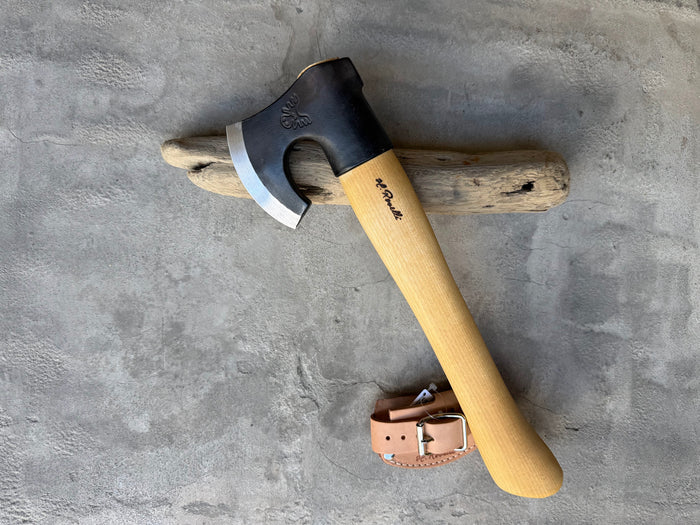 Roselli Short-Handle Axe R860 resting on driftwood with its leather sheath beside it