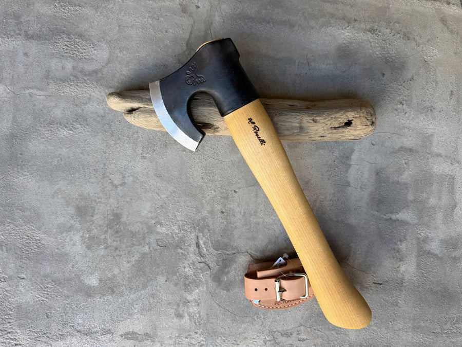 Roselli Short-Handle Axe R860 resting on driftwood with its leather sheath beside it